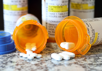 Open prescription medication bottles with some medication spilling out