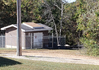 The mulberry well wellhouse, surrounded by chain-link fencing.