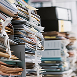 Several stacks of 3-ring binders, expandable files and other documents on a table.