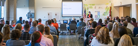 A department employee standing at the front of a conference room discussing issues with various stakeholders